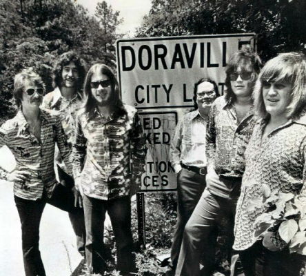 Members of the Atlanta Rhythm Section—(left to right) J.R. Cobb, Ronnie Hammond, Barry Bailey, Paul Goddard, Robert Nix, and Dean Daughtry—stand before a sign indicating the Doraville city limits.